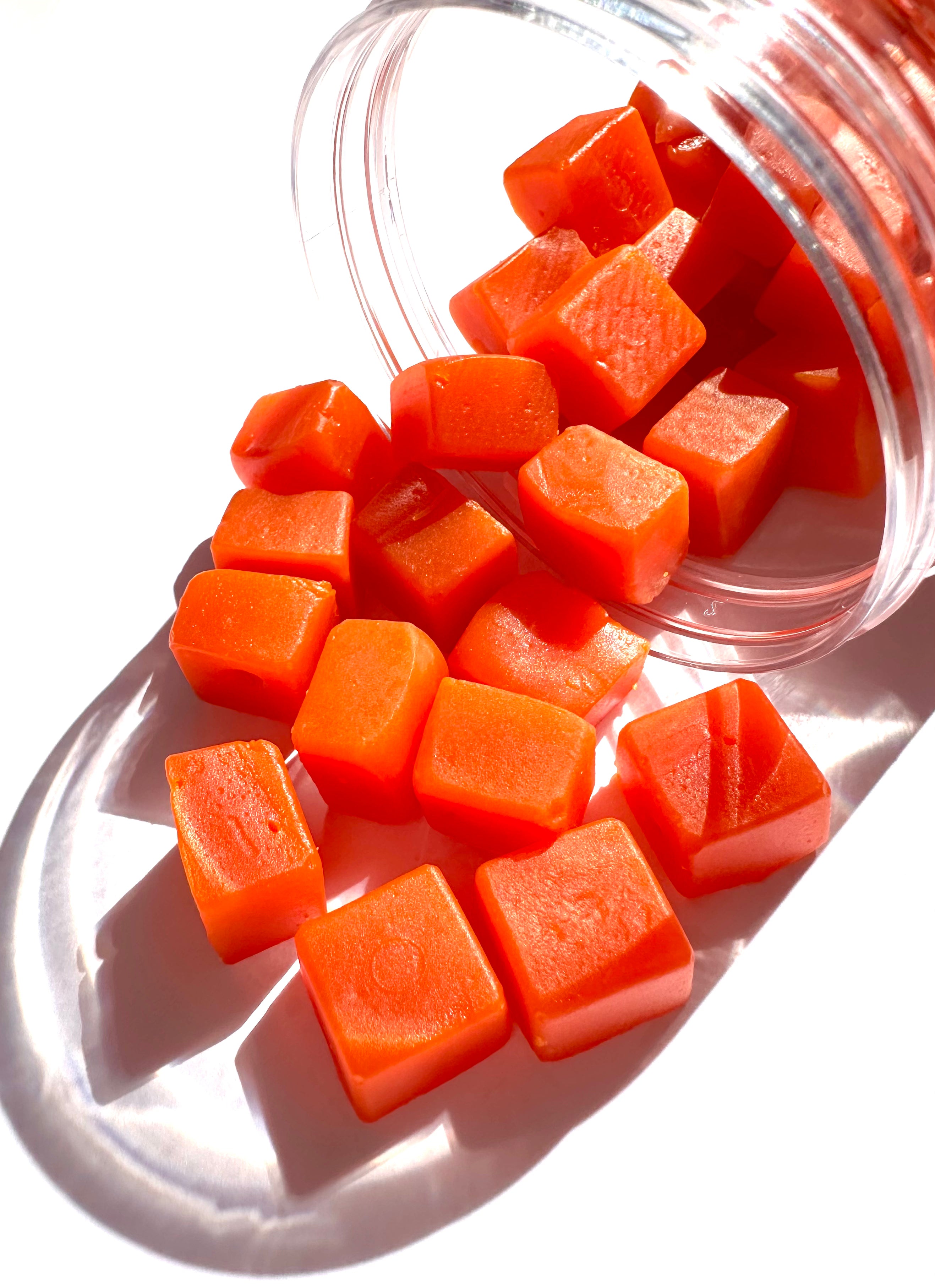 Macro close-up of Glotrition Afterglo gummies pouring from the jar, showing texture and vibrant golden berry color.